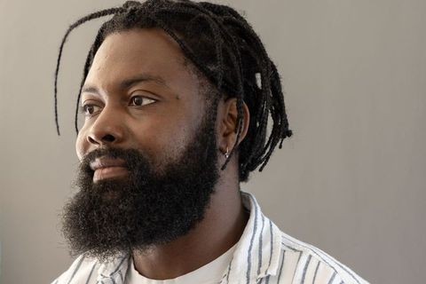 Thoughtful african man with dreadlocks and beard wearing striped shirt and hoop earring