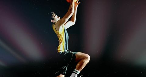 Soaring basketball player making powerful layup under dramatic arena spotlights