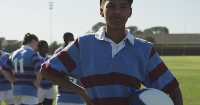 Confident Teen Holding Rugby Ball on Field with Teammates - Download Free Stock Images Pikwizard.com