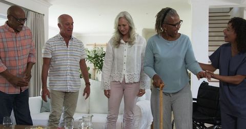 Senior friends support walking with caregiver at home