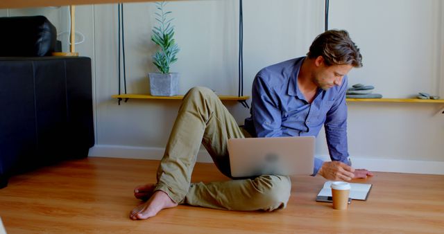 Remote Worker Sitting on Floor Using Laptop and Mobile Phone - Download Free Stock Images Pikwizard.com