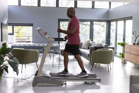 Senior Man Walking on Treadmill in Bright Living Room