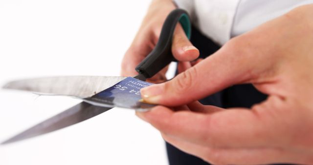 Close-up of hands cutting a credit card with scissors. Can be used to illustrate articles or content related to financial responsibility, debt reduction, personal finance, managing credit, or making important financial decisions.