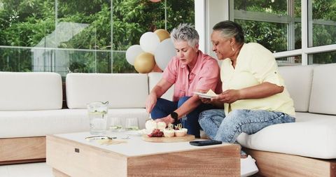 Senior Lesbian Couple Celebrating Birthday with Cake Outdoors