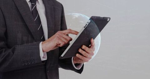Businessman holding tablet tapping screen with holographic globe overlay global analytics