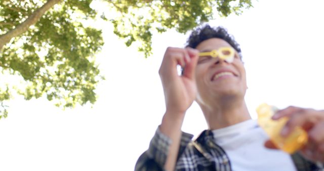 Joyful young man blowing bubbles outdoors on sunny day - Download Free Stock Images Pikwizard.com