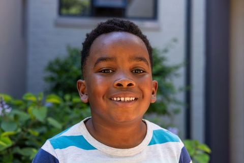 Smiling african american boy standing in home garden wearing striped t-shirt