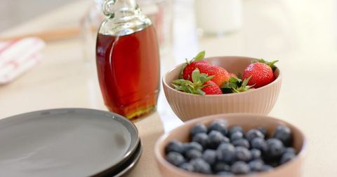 Displaying fresh strawberries and blueberries with maple syrup on minimal neutral countertop