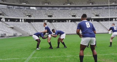 Rugby players forming intense scrum in empty stadium during team training session