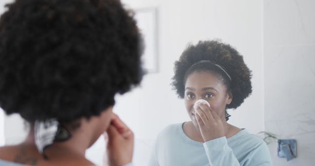 Woman Cleansing Face with Cotton Pad in Bathroom Mirror - Download Free Stock Images Pikwizard.com