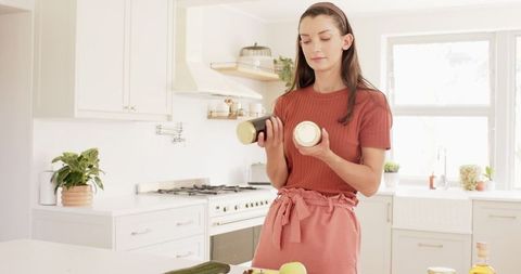 Woman Comparing Spice Jar Labels in Bright Modern Kitchen