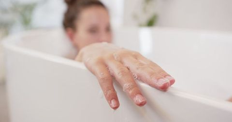 Woman relaxing in modern bathtub with soap suds