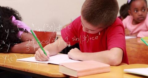 Young student writing equation in elementary school classroom