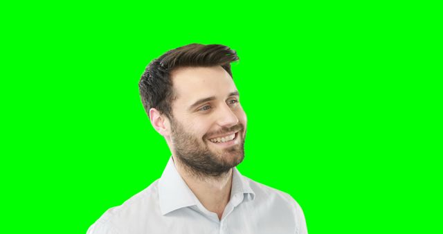 Smiling young man standing against green screen