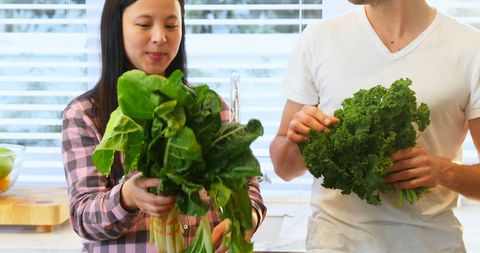 Diverse Couple Cooking with Fresh Greens in Kitchen