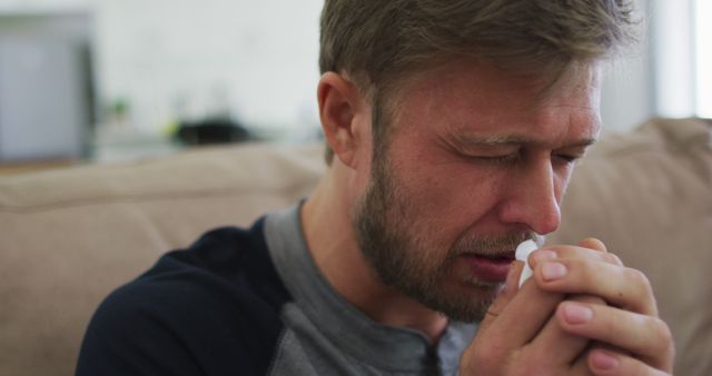 Man Blowing Nose Due to Cold, Feeling Unwell Indoors on Couch - Download Free Stock Images Pikwizard.com