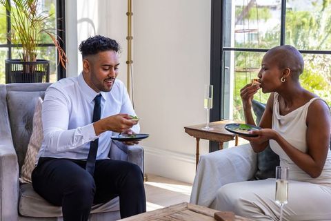 Couple enjoying appetizers and champagne in sunlit living room sharing intimate moment