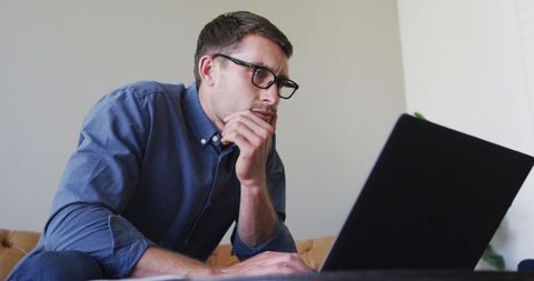Focused Man Wearing Glasses Working on Laptop at Home