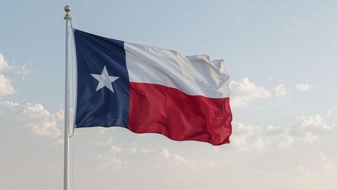 Waving Texas Flag Against Blue Sky with Clouds