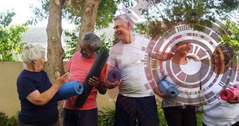 Seniors holding yoga mats in backyard garden smiling and preparing for group fitness