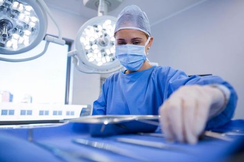 Woman Surgeon Prepares Instruments Under Operating Room Lights