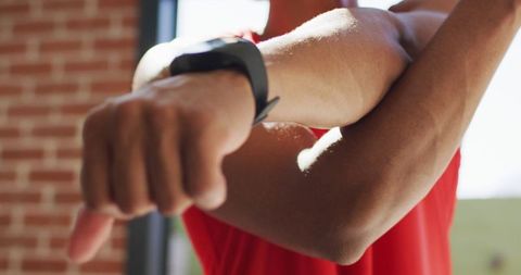 Athletic Man Stretching with Smartwatch Indoors