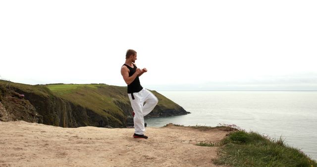 Martial Artist Practicing on Cliffside with Ocean View - Download Free Stock Images Pikwizard.com