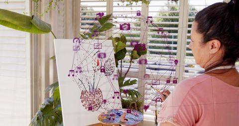 Artist painting botanical still life in sunlit home studio with augmented reality overlay