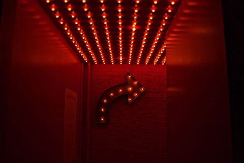Neon Arrow Sign in Dark Hallway with Red Lighting