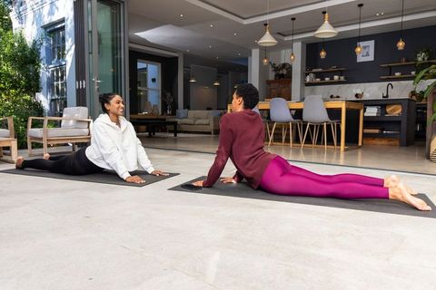 African american and indian women practicing yoga on modern open-plan terrace in cobra pose