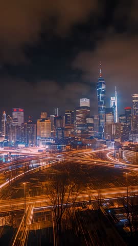 Vertical video showing light trails weaving through urban highway interchange with glowing skyline