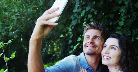 Happy couple taking selfie in lush green environment