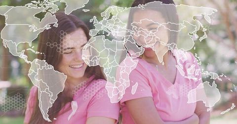 Global breast cancer awareness volunteers smiling in pink shirts with world map overlay