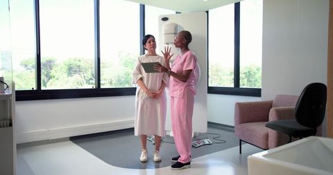 Patient and African American Radiology Tech Discussing Mammogram While Using Tablet in Clinic