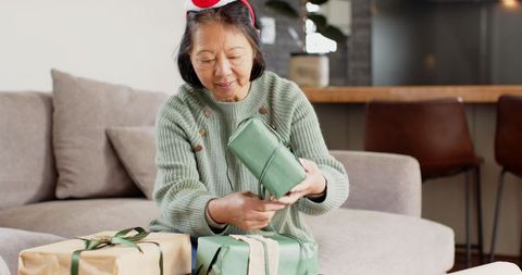 Senior Woman with Antlers Opening Christmas Gifts at Home