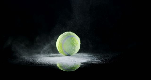 Tennis ball hitting surface and creating a spectacular dust cloud on black background. Perfect for use in sports advertising, background images for tennis-related articles or websites, and promotional materials for tennis games or tournaments.