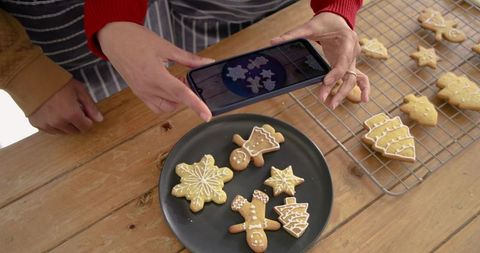 Friends capturing decorated gingerbread cookies on wooden table for holiday baking content