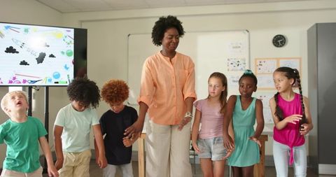 African American Teacher Guiding Diverse Elementary Students in Classroom Group Activity
