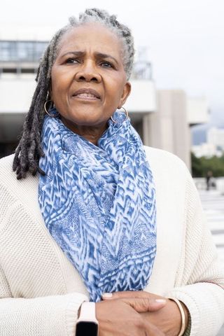 Senior african american woman gazing upward on urban terrace wearing blue patterned scarf