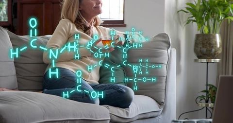 Relaxing woman enjoying tea with neon molecular overlay on cozy living room couch