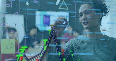 Woman drawing data chart on glass board during collaborative team meeting