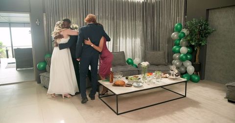 Multiracial Wedding Reception Group Hug in Modern Living Room