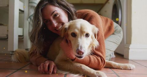 Smiling woman hugging light-colored dog on terracotta tile floor cozy laundry room moment