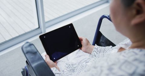 Patient in Hospital Gown Using Tablet in Wheelchair - Download Free Stock Images Pikwizard.com