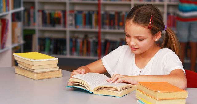 Young Girl Reading Book at Library Table Surrounded by Books - Download Free Stock Images Pikwizard.com