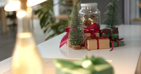 Minimal holiday tabletop featuring bottle-brush trees, wrapped gifts and jar lights