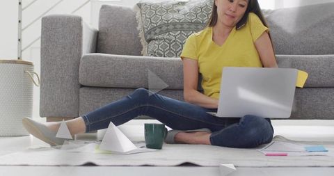 Remote worker sitting on floor with laptop and phone in cozy living room