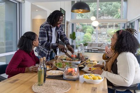 African American Family Sharing Home-Cooked Meal Around Wooden Table in Sunlit Open Plan