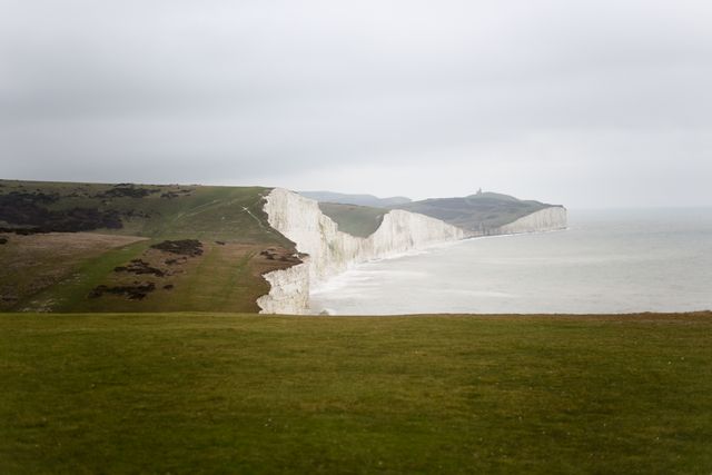 This image captures the stunning white cliffs along the coast of England under a cloudy sky, offering a dramatic and scenic view. Ideal for use in travel blogs, UK tourism promotions, environmental awareness campaigns, and landscape photography collections.