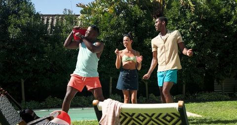 Celebrating Friends Dancing by Pool with Drinks and Cooler